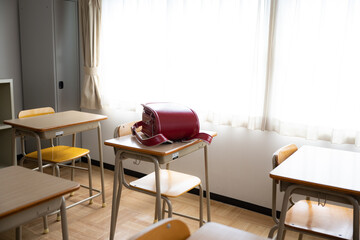 小学校の机に置かれた赤いランドセル 広角