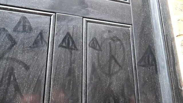 Dirty wooden door with the Deathly Hallows painted in a house of Goodwin's Court