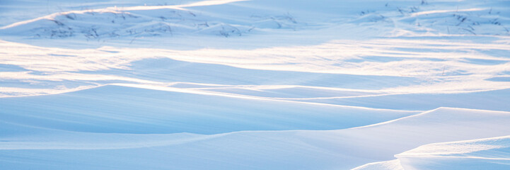 Snow texture. Wind sculpted patterns on snow surface. Wind in the tundra and in the mountains on the surface of the snow sculpts patterns and ridges. Arctic, Polar region. Winter panoramic background.