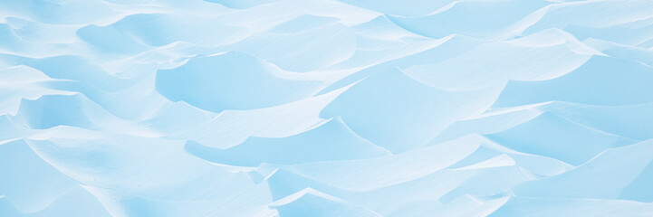 Snow texture. Wind sculpted patterns on snow surface. Wind in the tundra and in the mountains on the surface of the snow sculpts patterns and ridges (sastrugi). Arctic, Polar region. Winter background