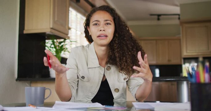 Happy biracial woman gesturing on video call in kitchen