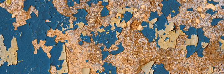 Peeling paint on the wall. Panorama of a concrete wall with old cracked flaking paint. Weathered rough painted surface with patterns of cracks and peeling. Wide panoramic texture for design background