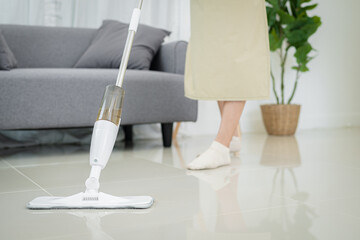 Beautiful Asian woman cleaning living room in house Sweeping the floor using microfiber wet mop pad. homework cleaning routine. Domestic House keeping concept