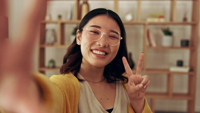 Portrait, selfie or Asian woman with peace sign or smile in house live streaming for social media content. Japanese, happy or girl video recording or taking photos for online profile pictures at home
