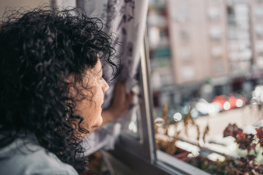 Older Woman Looking Out Of Her Terrace Window.