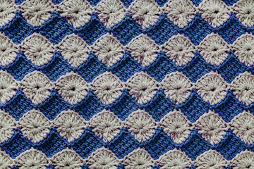 White and blue crochet floral pattern. Crochet tunisian pattern. Knitted texture.