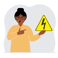 A woman holds a yellow triangular warning sign with a black lightning in his hand. The concept of the danger of electric shock or high voltage.
