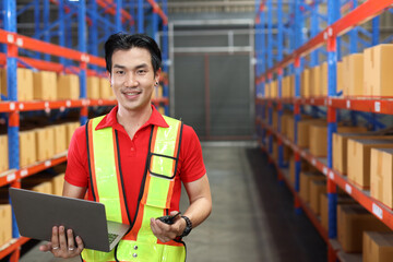 Warehouse workers man with hardhats and reflective jackets using computer, walkie talkie radio and cardboard while controlling stock and inventory in retail warehouse logistics, distribution center