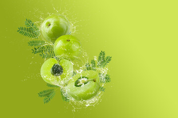 Creative layout made from Fresh Sliced Emblic or Indian gooseberry and water Splashing on a green background.