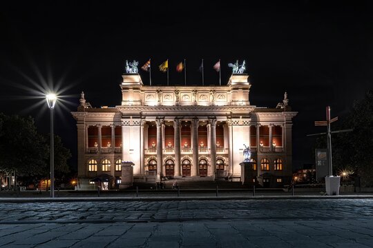 Illuminated Royal Museum of Fine Arts Antwerp with country flags at night