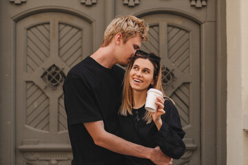 Attractive young romantic couple standing near door, hugging, man hug woman and tell something on...