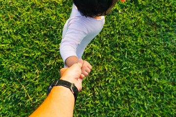 Unrecognizable father's hand lead his child son in summer forest nature outdoor, trust family concept