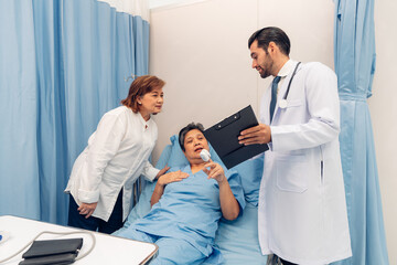 Obraz premium Hospitalized woman lying in bed while doctor checking his pulse. Doctor examining senior female patient in hospital room.