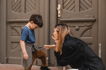Mother scolds her son on the street. A child cries, a woman shakes her finger because of the boy...