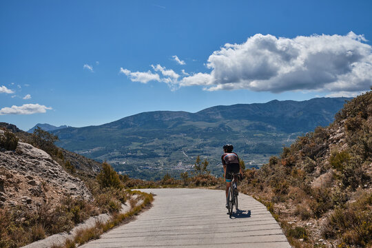 Man riding gravel bike on gravel road in mountains with scenic view.Gravel cycling adventure.Beautiful motivation image of an athlete.Guadalest Reservoir,Alicante,Spain.