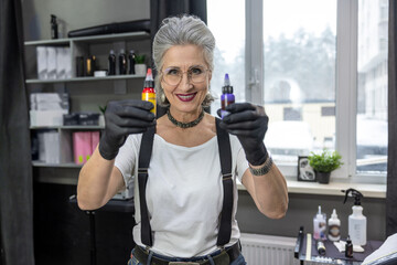 Female tattoo master holding bottles with tattoo ink