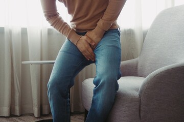 Man using his hands touching and covering his crotch suffering from his genitourinary system or...