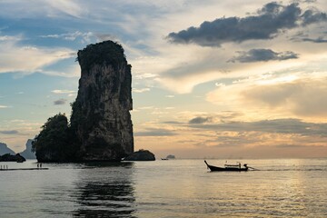 Fototapeta na wymiar Huge stack and a boat at the Pai Plong Beach with sunset in the background in Krabi, Thailand