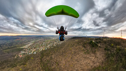 Paragliding flying over Budapest at dramatic cloudy sky