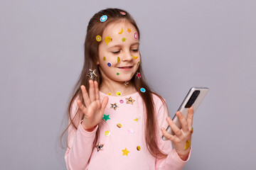 Photo of cute confident little brown haired little girl covered with stickers posing isolated over...