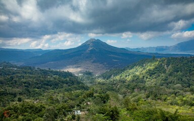 Green landscape before the Mount Batur under the cloudy sky