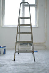 Folding metal ladder-stepladder against the background of painted walls in the room.