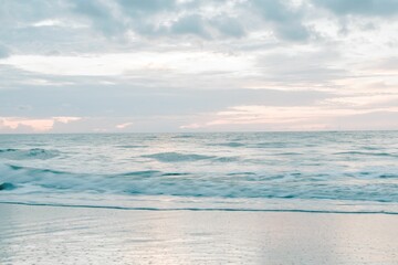 Scenic shot of foamy waves of the sea crashing the shore at sunrise