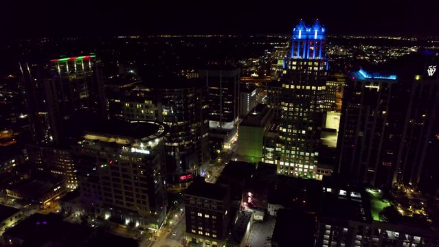 Drone view of illuminated cityscape with skyscrapers and high- rise buildings in downtown at night