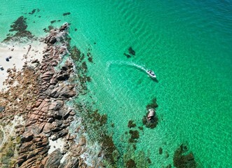 Drone view of a motorboat boating at the coastline on a sunny day