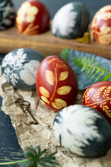 Easter eggs dyed with natural ingredients like cabbage, onion peel, hibiscus tea carcade with beatiful patern on rustic wooden tray and craft paper.