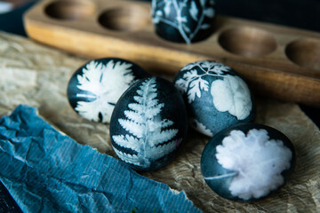 Easter eggs dyed with natural ingredients like cabbage, onion peel, hibiscus tea carcade with beatiful patern on rustic wooden tray and craft paper.