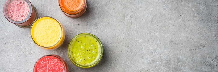 Glasses of fresh juice on gray stone table. Food background