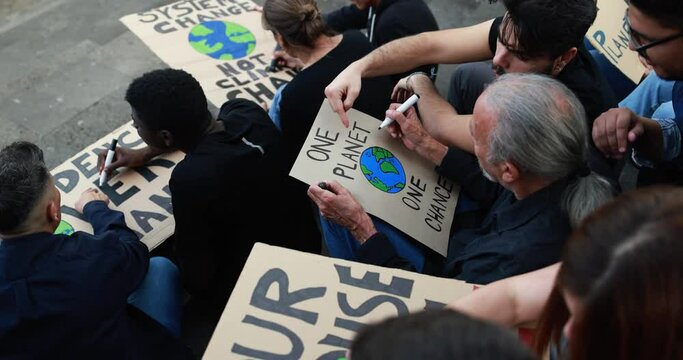 Group of demonstrators prepare banners for protest in the city - Multigenerational people from different culture and race fight for climate change