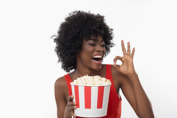 Happy dark skin female with popcorn is ready to watch new movie.
