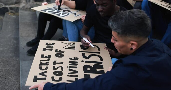 Crowd of multiracial people protest against inflation and financial crisis - Protesters prepare banners before marching for rise cost of living