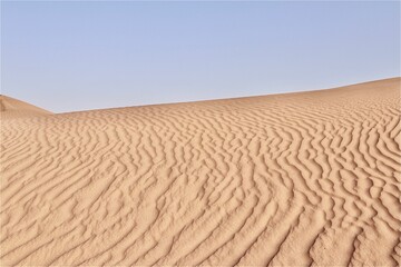 Scenic view of desert against sky under the clear blue sky with the sun shining bright