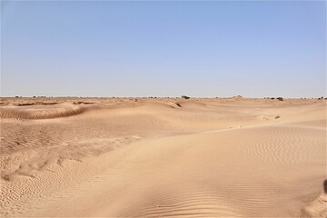 Scenic view of desert against sky under the clear blue sky with the sun shining bright