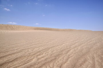 Sand in the dry desert on a sunny day against a blue sky