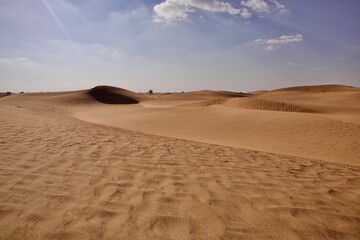 Fototapeta na wymiar Sand in the dry desert on a sunny day against a blue sky