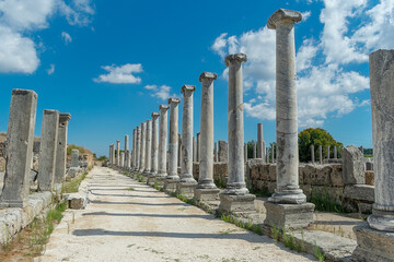 Fototapeta premium Agora of the ancient city of Perge in clear sunny weather. Against the background of a blue sky with clouds.