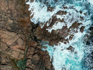 Aerial view of the coast with rocks and blue ocean waves in daylight