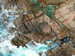 Aerial view of the coast with rocks and blue ocean waves in daylight