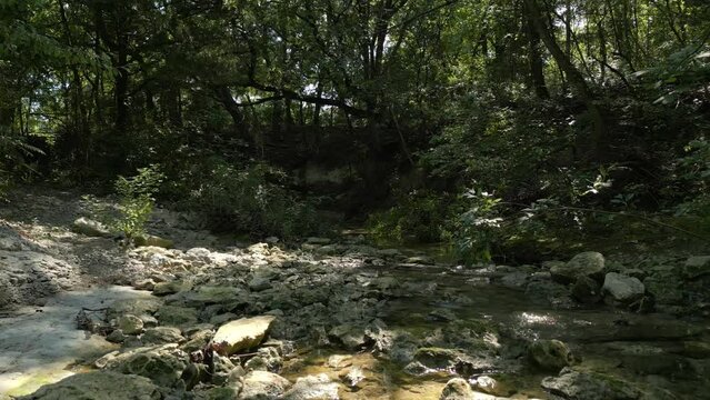 Beautiful view of woods in Lost Creek in Allen TX with river, rocks and light falling from trees