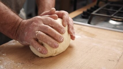 Male hands kneading dough, baking preparation closeup. Pastry Man kneads making yeast dough for pizza, burger, buns, muffins or pie. Anonymous baker. Bakery chef cooking bake in a kitchen professional