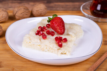 Güllaç dessert with pomegranate and strawberry. Ramadan dessert. Gullac dessert with walnuts on wooden background. Close up