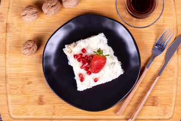 Güllaç dessert with pomegranate and strawberry. Ramadan dessert. Gullac dessert with walnuts on wooden background. Top view