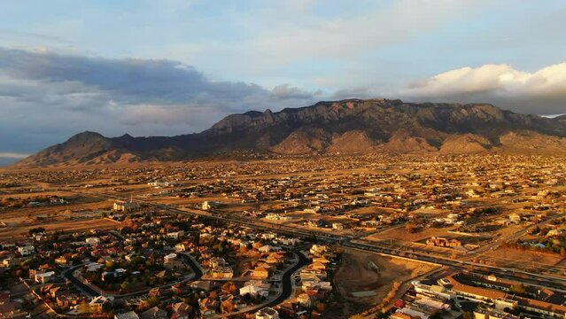 Aerial drone golden sunset toward Sandia Mountains Albuquerque New Mexico with adobe homes pan up