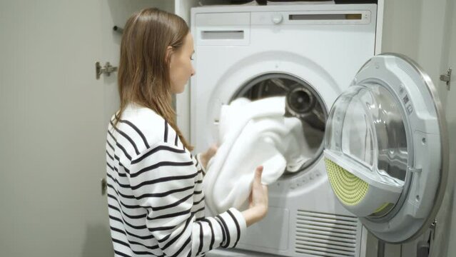 Beautiful woman sniffs white towels after washing in the washing machine. 
