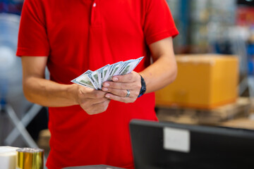 Hands counting money dollar bills. warehouse man worker wearing hard hat helmet and working at warehouse factory. Wholesale Merchandise. shelves, pallets and boxes