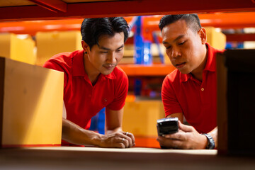 Warehouse manager staff working on barcode scanner handheld at warehouse factory. Trainee learning on the job